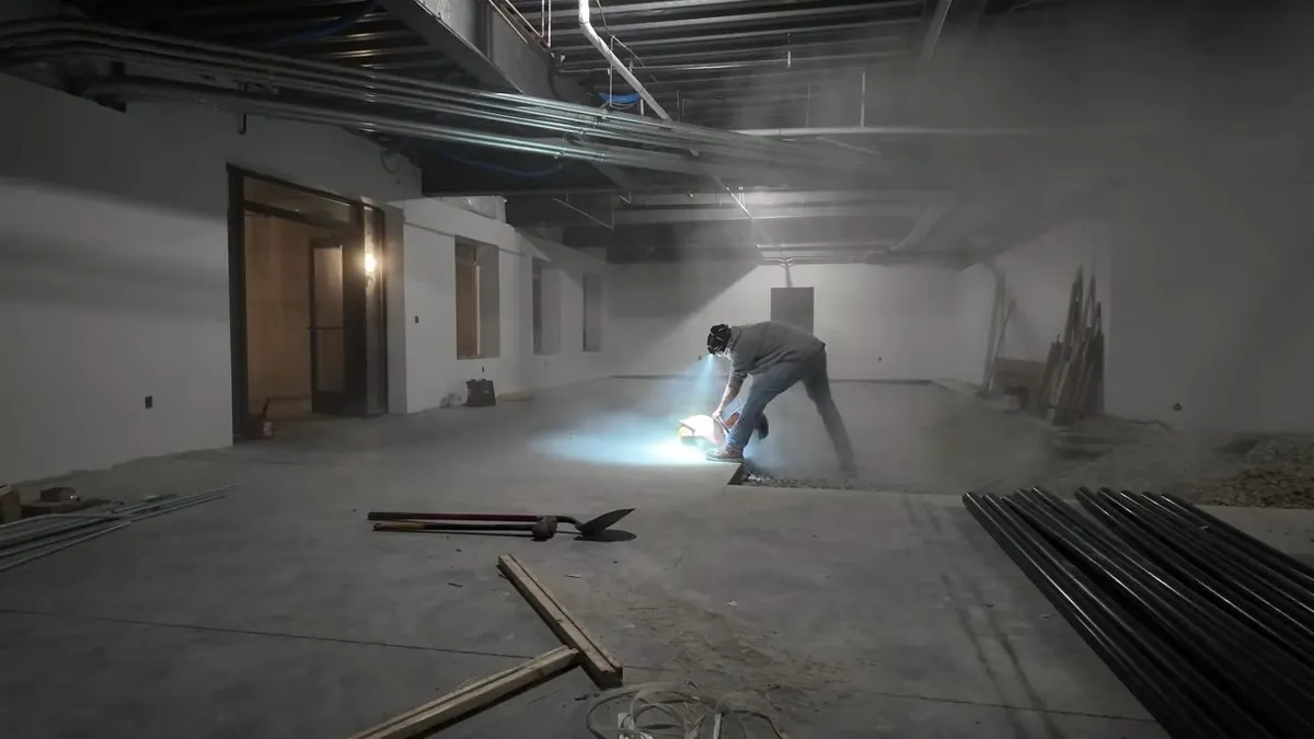 worker marks the floor in a large unfinished commercial build-out for Maricopa AZ Plumbing Guys