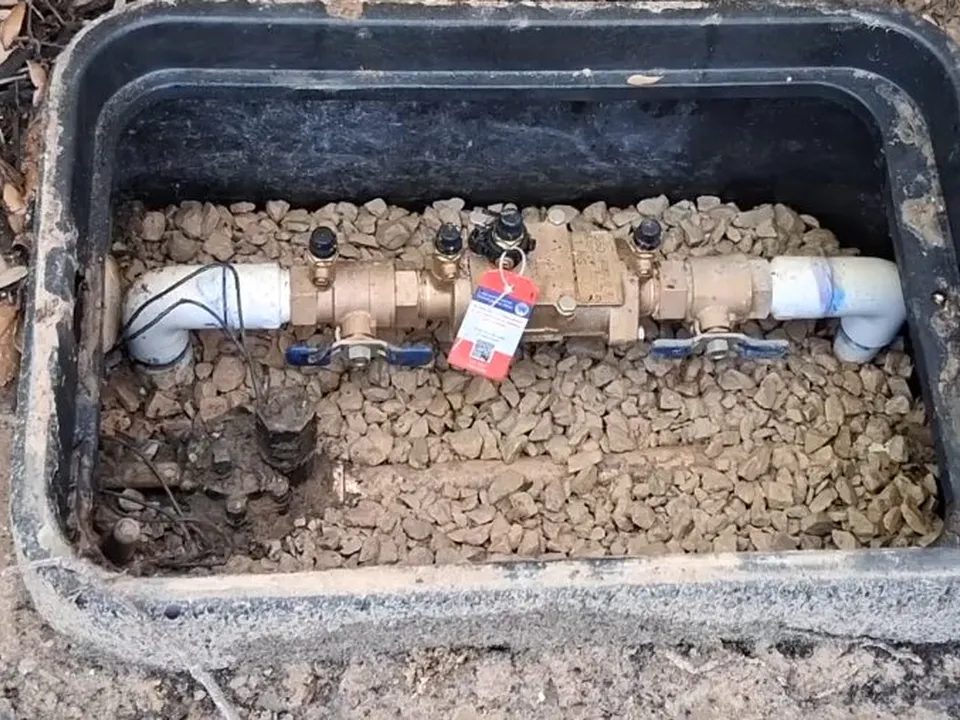 buried backflow assembly sits inside a rectangular ground-level valve box for backflow testing & prevention in maricopa, az in Maricopa