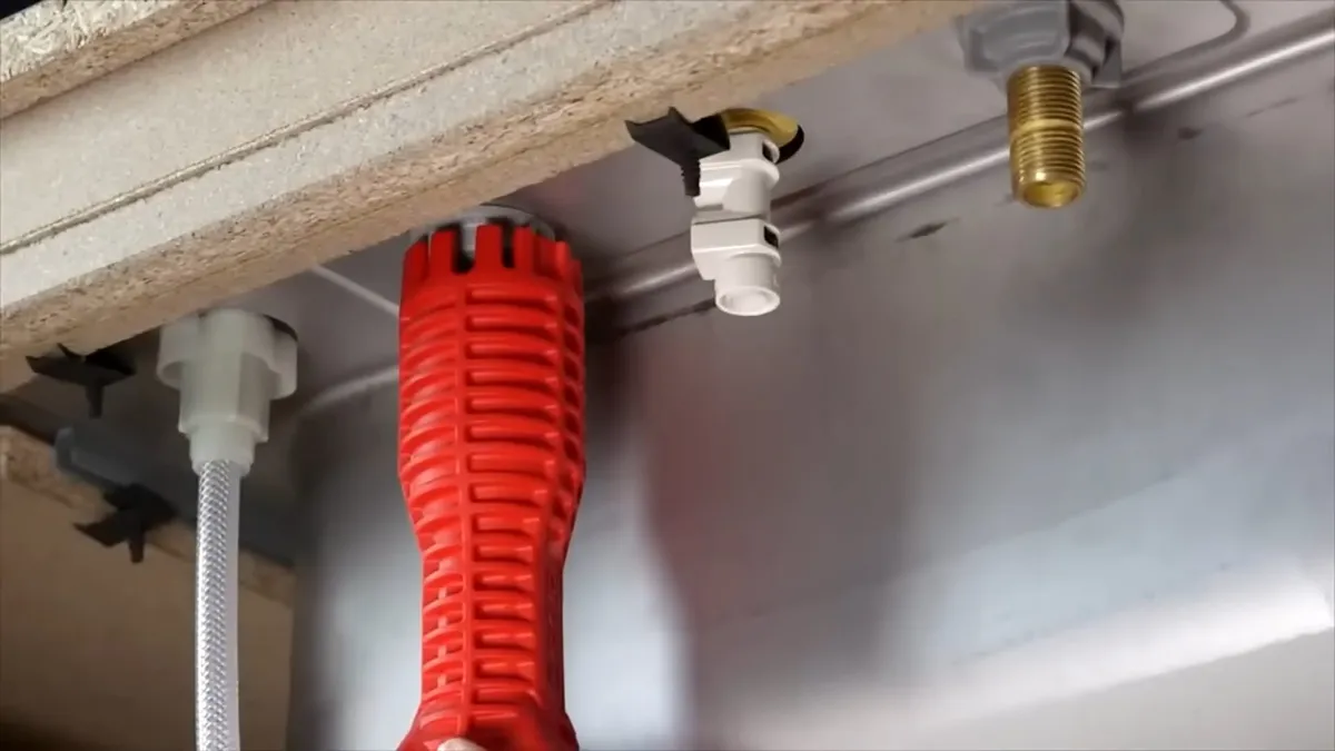 red flexible drain-cleaning tool hangs below a sink deck during a plumbing service call in Maricopa, AZ
