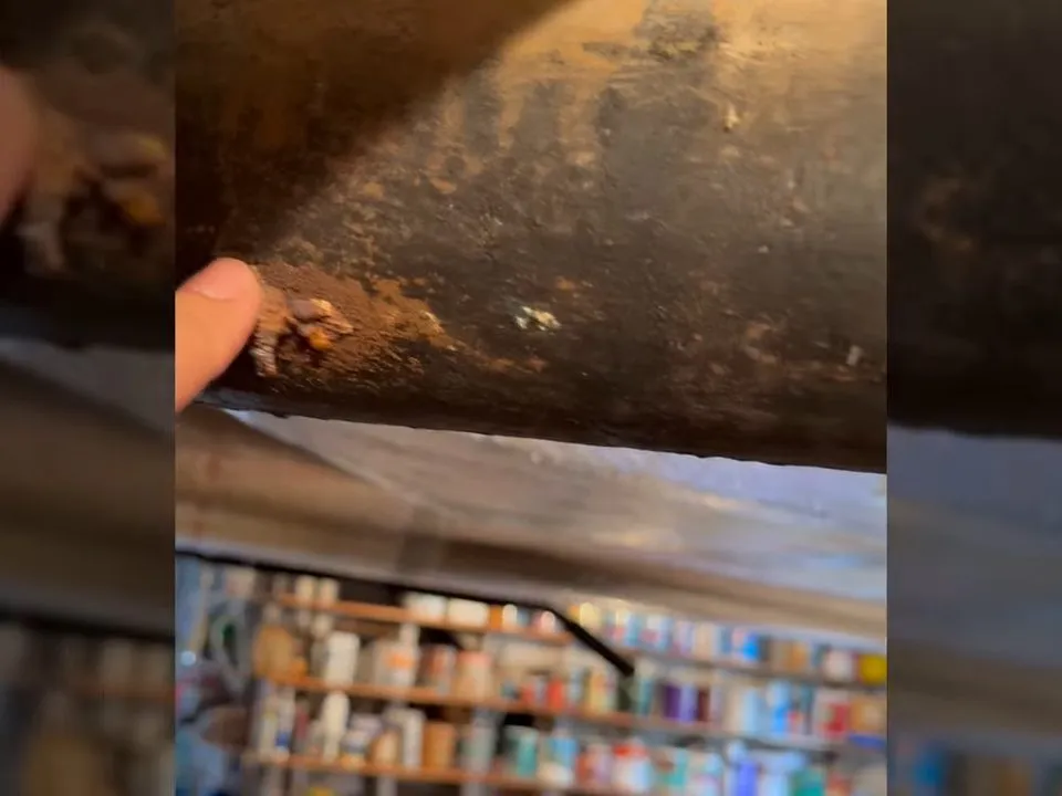 close-up reveals heavy rust and scaling on the outside of an old cast iron drain pipe during a plumbing service call in Maricopa, AZ