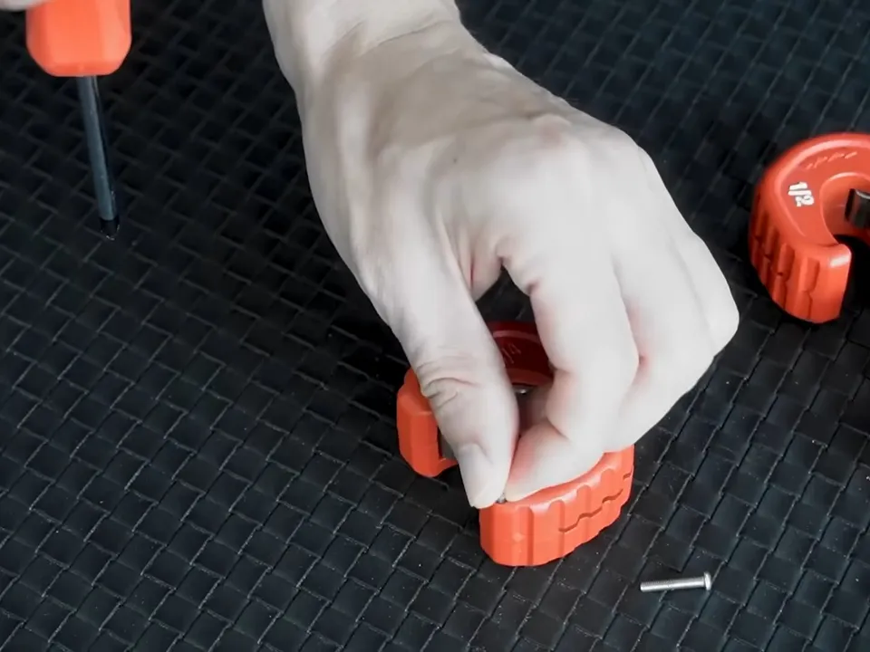 Small red pipe tools and replacement blades are arranged on a rubber work mat during a plumbing service call in Maricopa, AZ