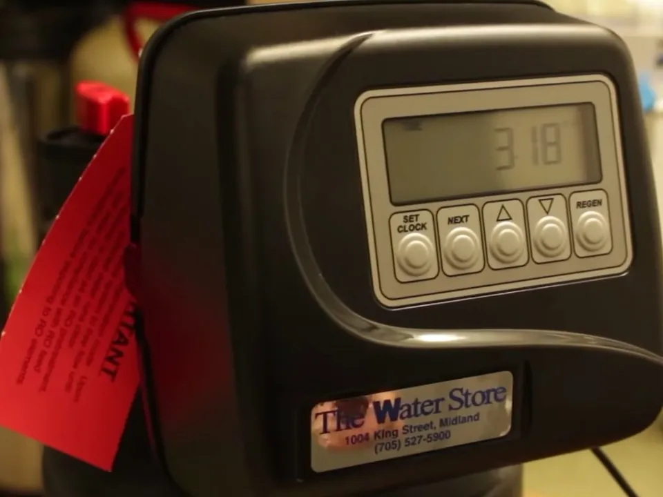 digital water-softener control head displays the programmed settings during a plumbing service call in Maricopa, AZ