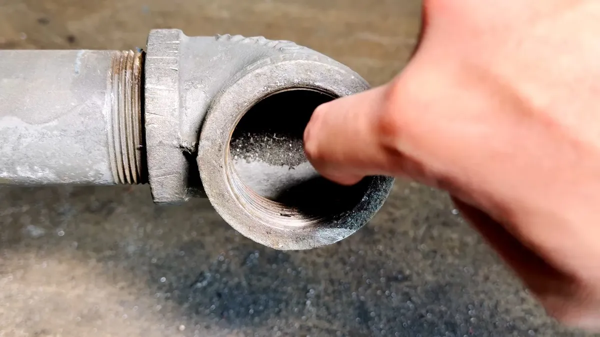 finger checks the opening inside a cast iron cleanout after the plug is removed for drain cleaning & unclogging in maricopa, az in Maricopa