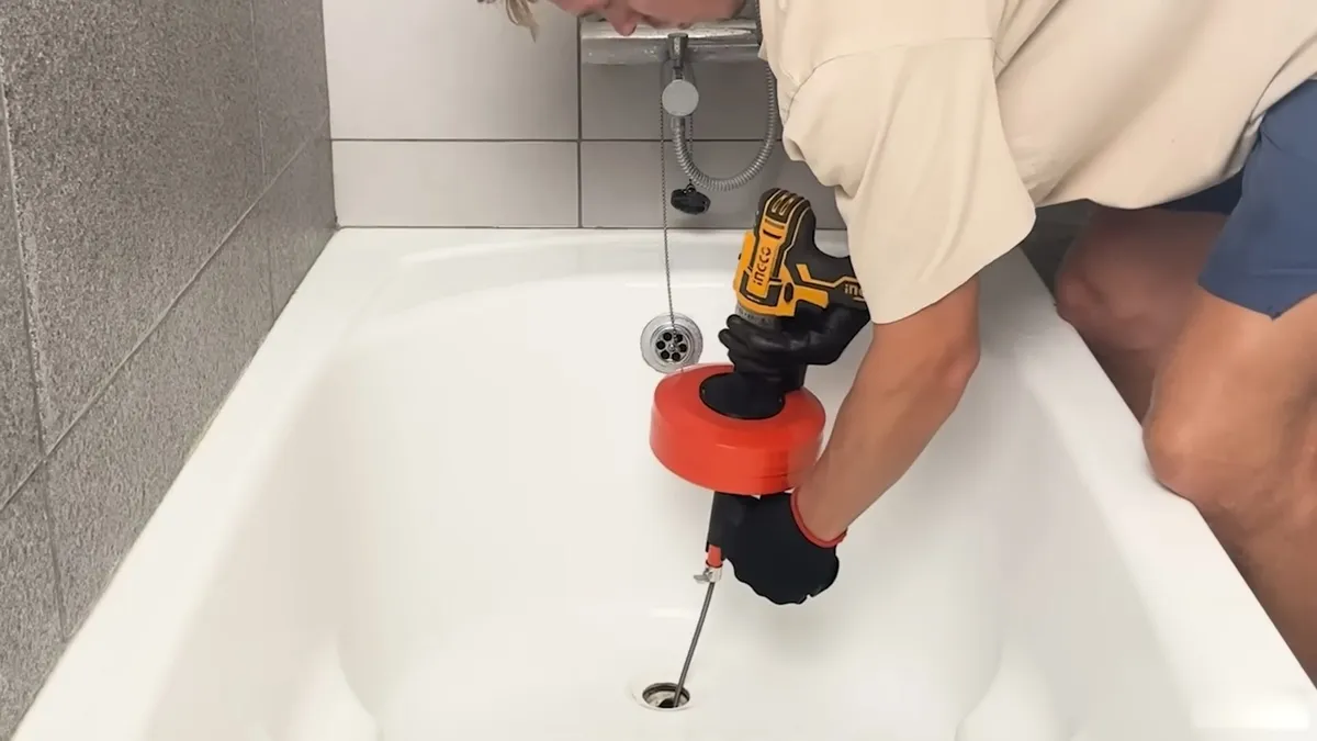 plumber feeds a compact drain auger into a bathtub drain for drain cleaning & unclogging in maricopa, az in Maricopa