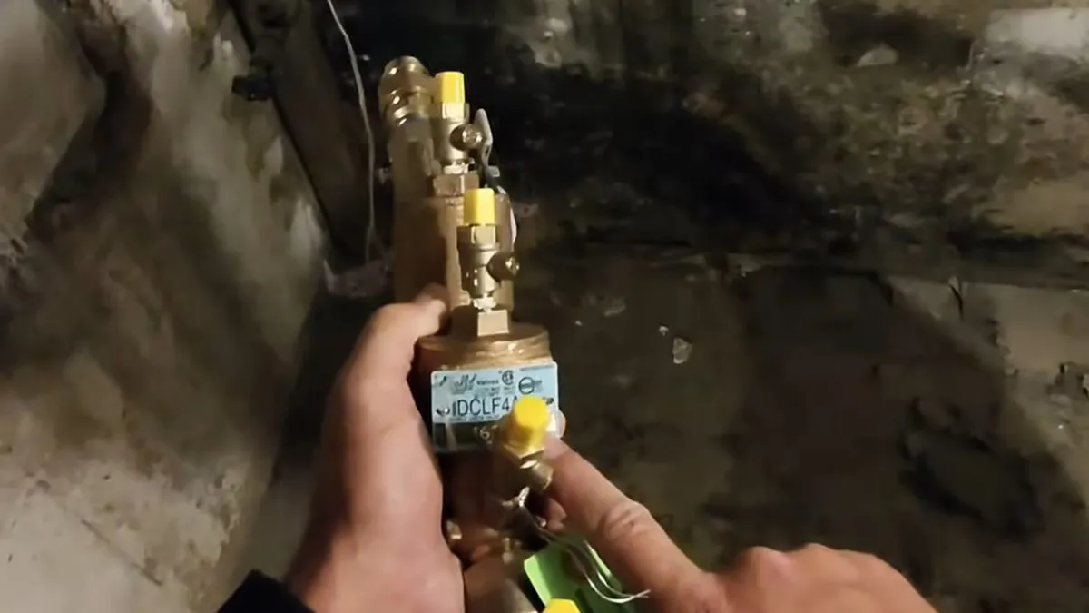 brass backflow valve is being assembled in a below-grade service area during a plumbing service call in Maricopa, AZ