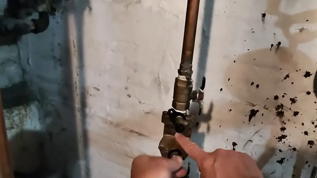 wrench tightens a valve on a vertical copper line against a utility-room wall during a plumbing service call in Maricopa, AZ