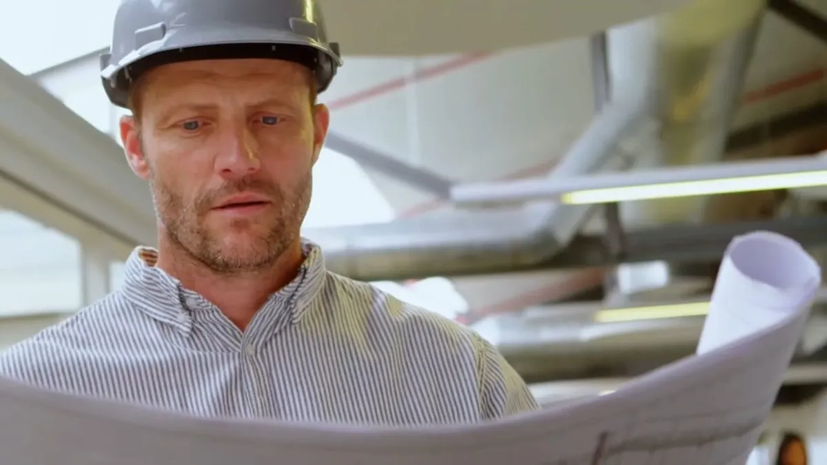 hard-hat technician studies building plans inside a mechanical work area for 24/7 emergency plumber in maricopa, az in Maricopa