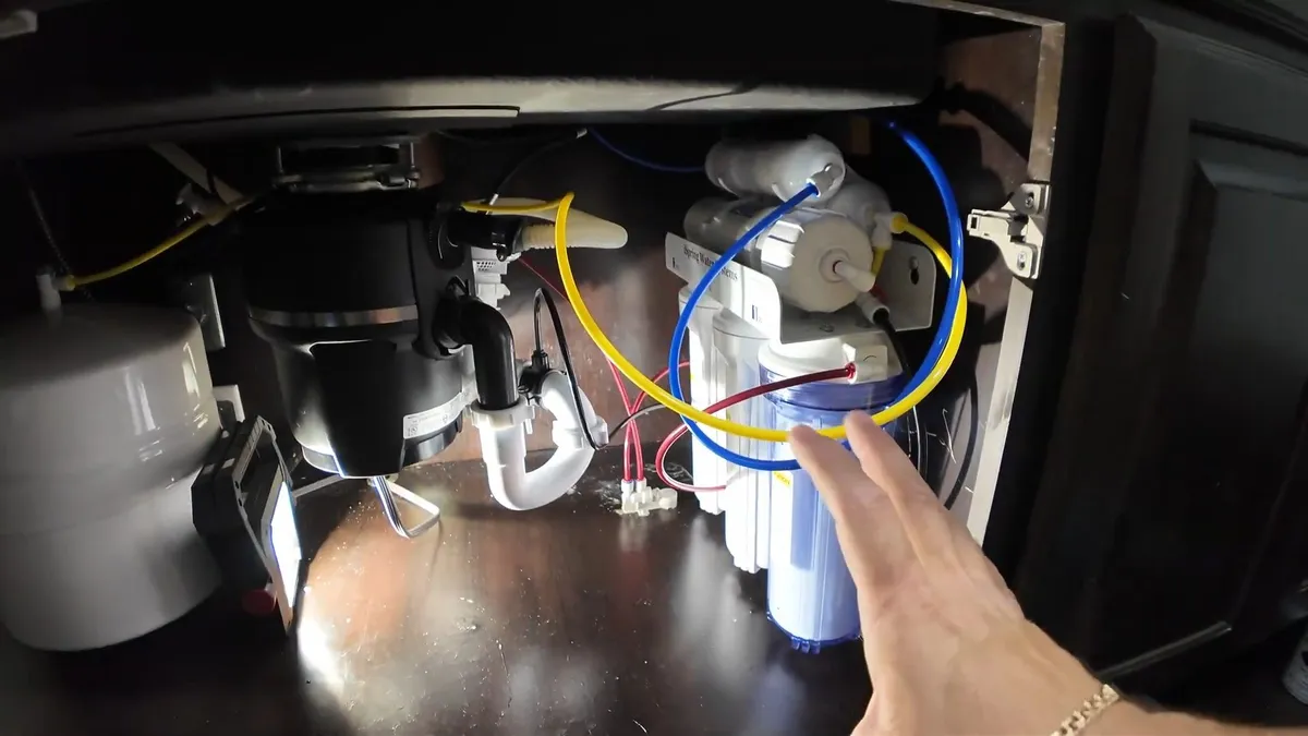 garbage disposal and nearby filter lines are exposed inside a sink cabinet for garbage disposal repair & installation in maricopa, az in Maricopa