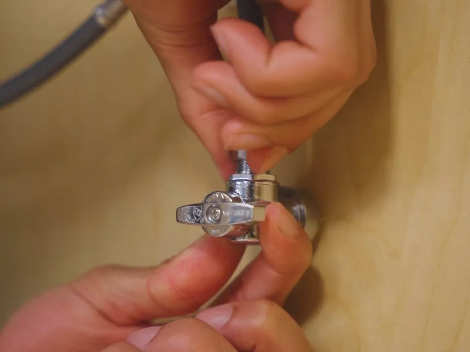 small shutoff valve is tightened on flexible tubing inside a cabinet for garbage disposal repair & installation in maricopa, az in Maricopa