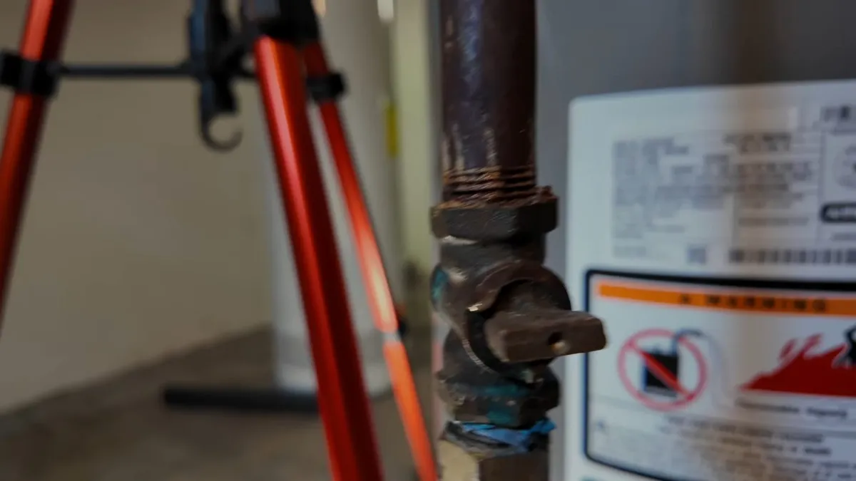 hand points to the gas shutoff valve and supply line beside a water heater for gas line installation & repair in maricopa, az in Maricopa