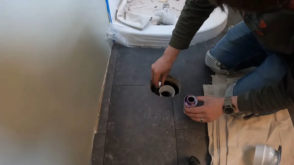 plumber compares two drain fittings above a newly opened bathroom floor during a plumbing service call in Maricopa, AZ