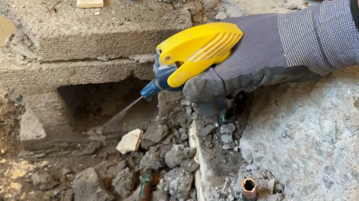 worker cuts into concrete beside an exposed pipe during bathroom demolition during a plumbing service call in Maricopa, AZ