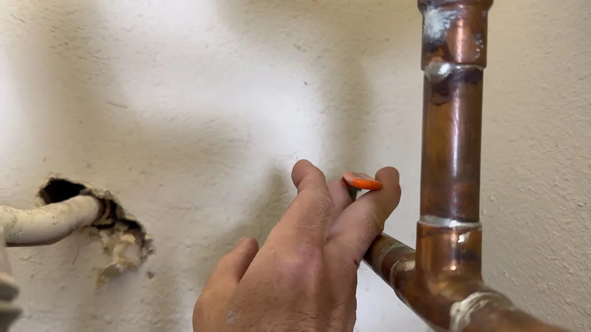 wrench loosens the anode-rod connection on top of a tank water heater illustrating How Hard Water from Global Water Resources Shortens Water Heater Life in Maricopa