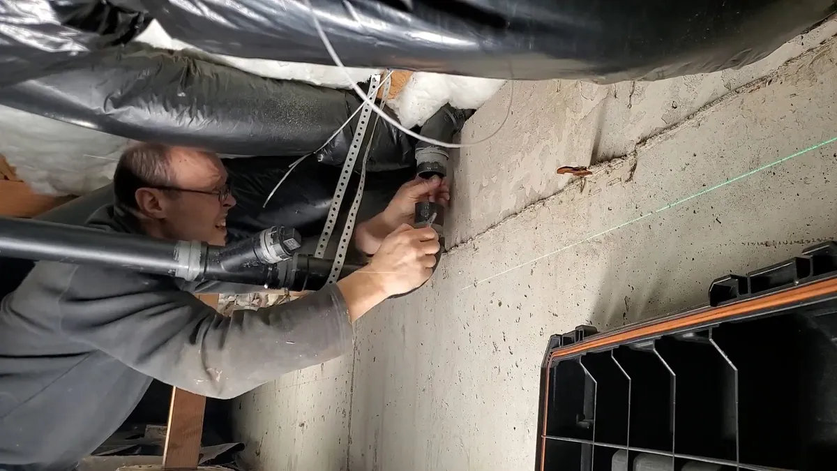 plumber adjusts drain piping inside a low crawlspace during a plumbing service call in Maricopa, AZ
