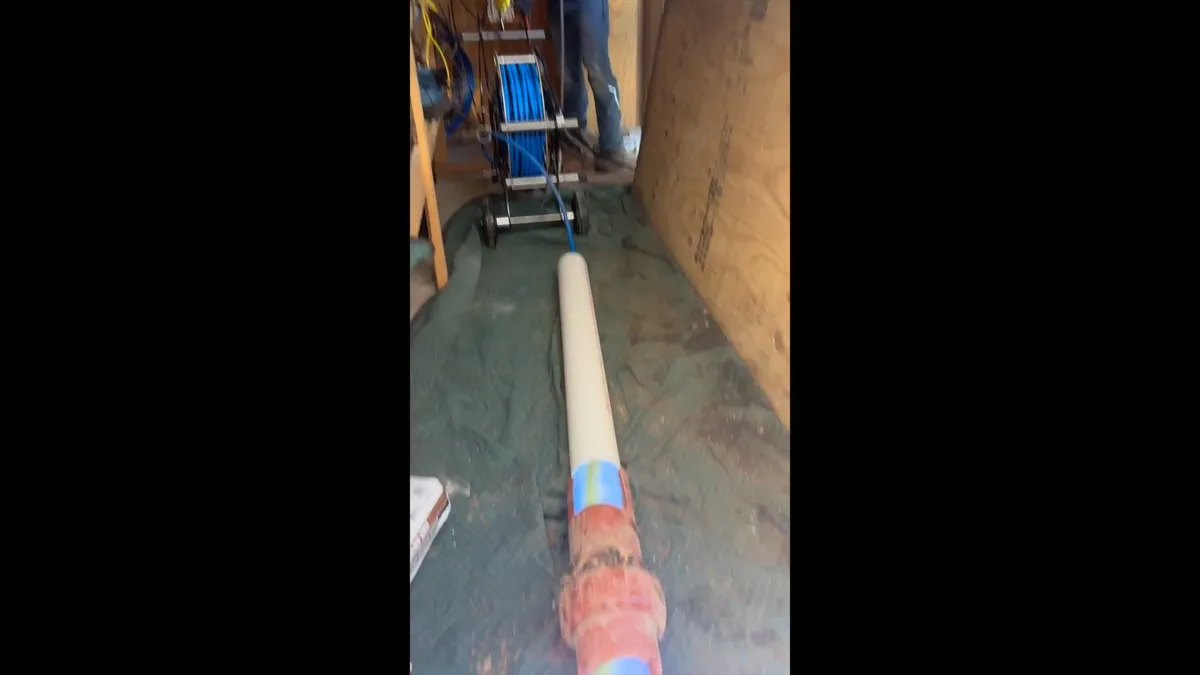long cured-in-place liner extends through a narrow service area during a plumbing service call in Maricopa, AZ