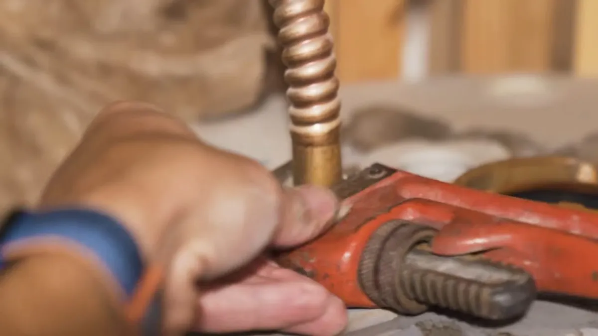 pipe wrench turns a flexible metal water-heater connector during a plumbing service call in Maricopa, AZ