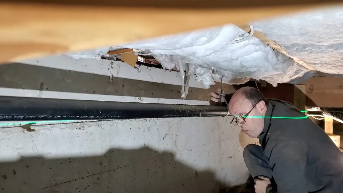 green laser line helps verify drain slope in a confined underfloor area during a plumbing service call in Maricopa, AZ