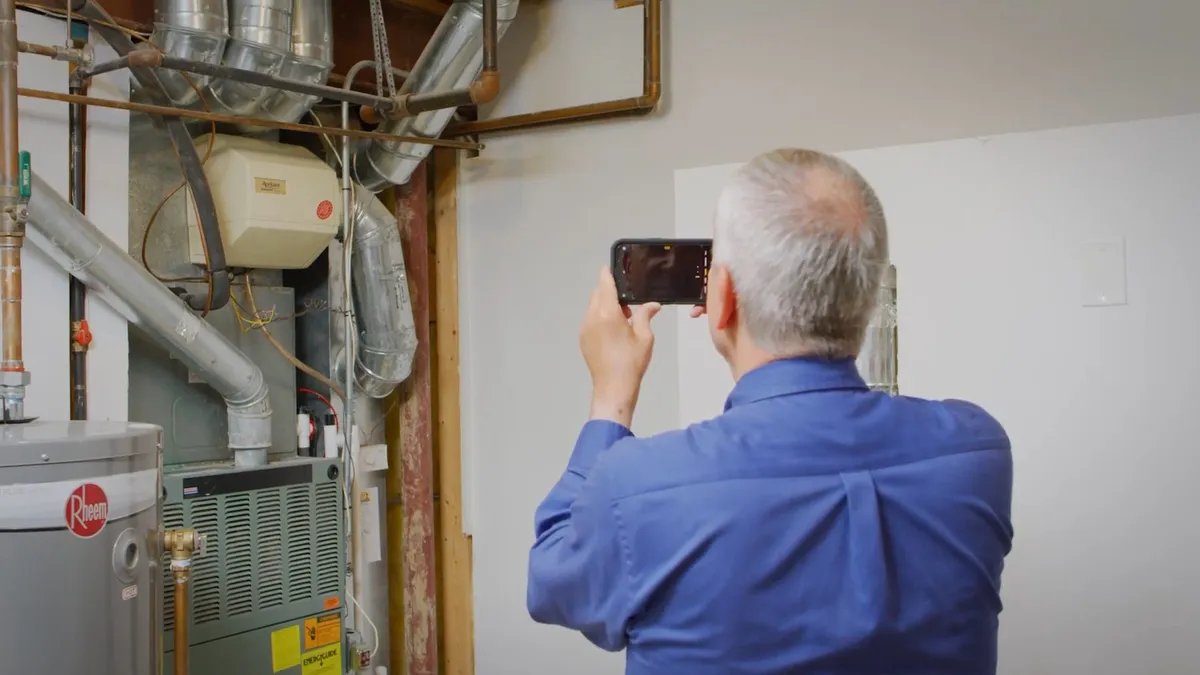 technician photographs water-treatment and heater equipment in a utility room for Maricopa AZ Plumbing Guys