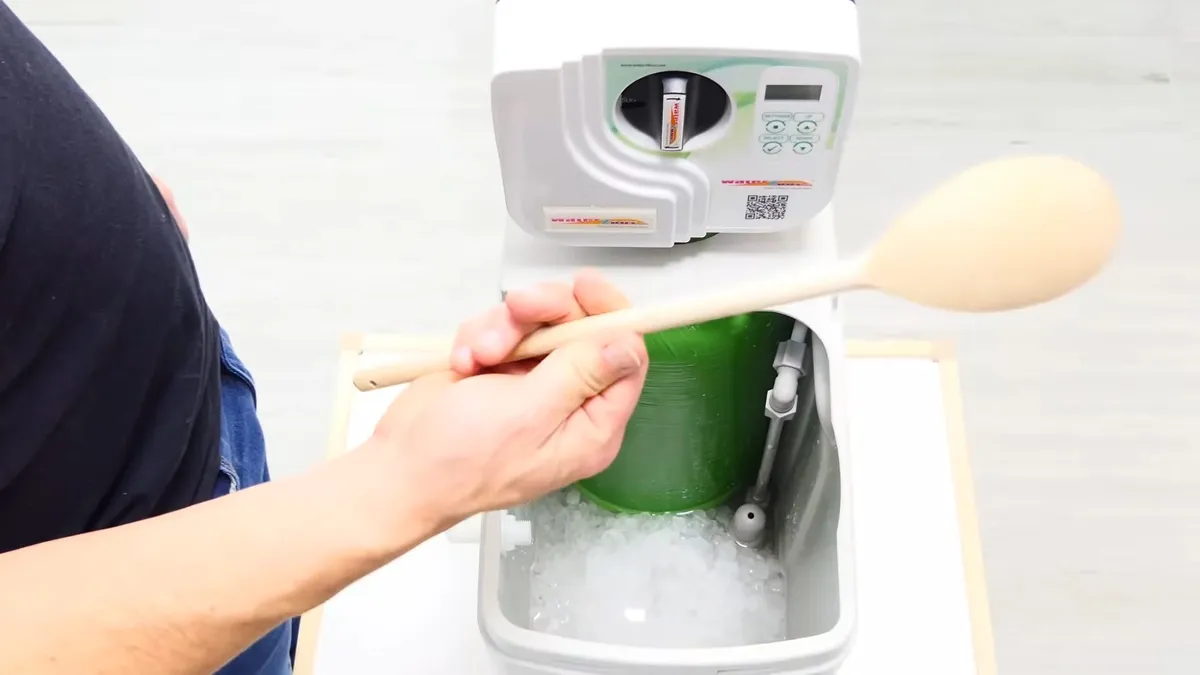spoon-shaped test paddle is held over a brine tank during a water-hardness check illustrating How Hard Is Maricopa's Water from Global Water Resources? A Homeowner's Guide
