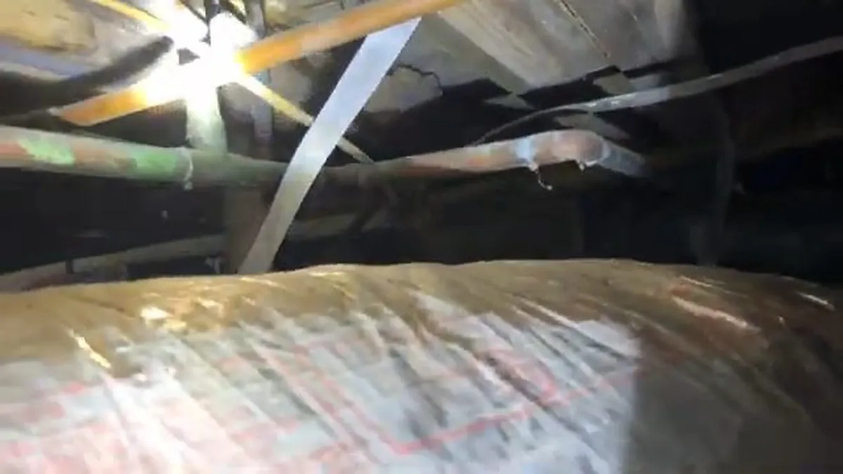 Damaged insulation and hidden piping are visible beneath a home floor during a plumbing service call in Maricopa, AZ