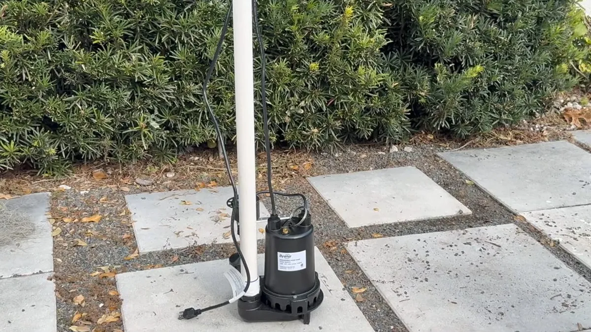 portable pump stands on an outdoor paved area beside its discharge hose for pool leak detection & repair in maricopa, az in Maricopa