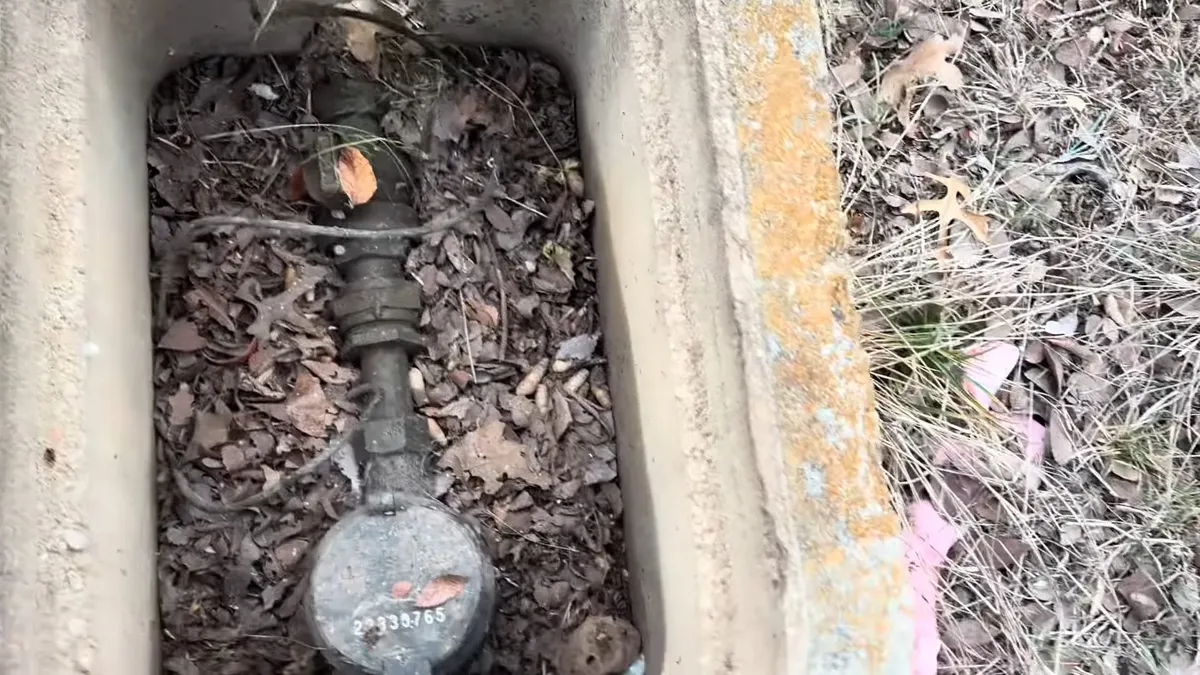 residential water meter sits below grade beneath leaves and soil illustrating Plumbing Tips for Province Snowbirds: Before You Leave Maricopa and When You Return