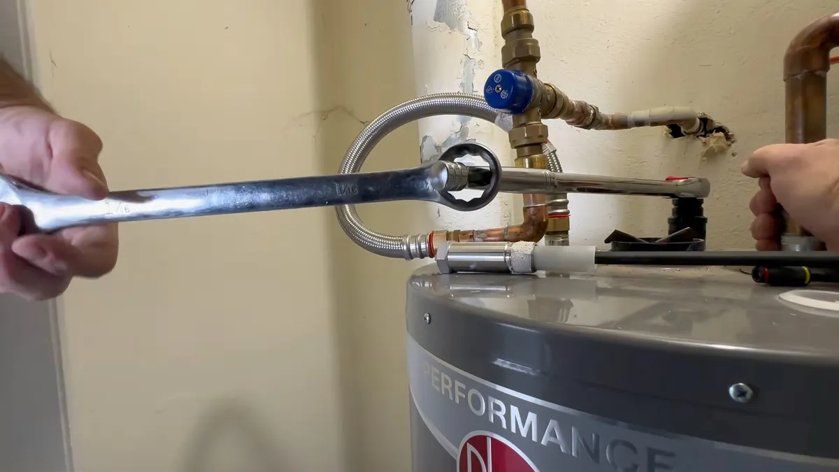 socket wrench turns the anode fitting while the heater top remains open illustrating Plumbing Tips for Province Snowbirds: Before You Leave Maricopa and When You Return