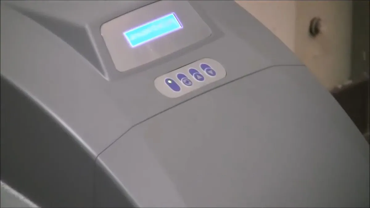 close-up shows the illuminated display and buttons on a softener controller during a plumbing service call in Maricopa, AZ