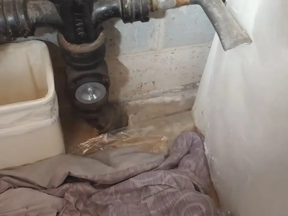 Corrosion and staining surround an old cast iron drain connection beside a utility sink for sewer line repair in maricopa, az in Maricopa