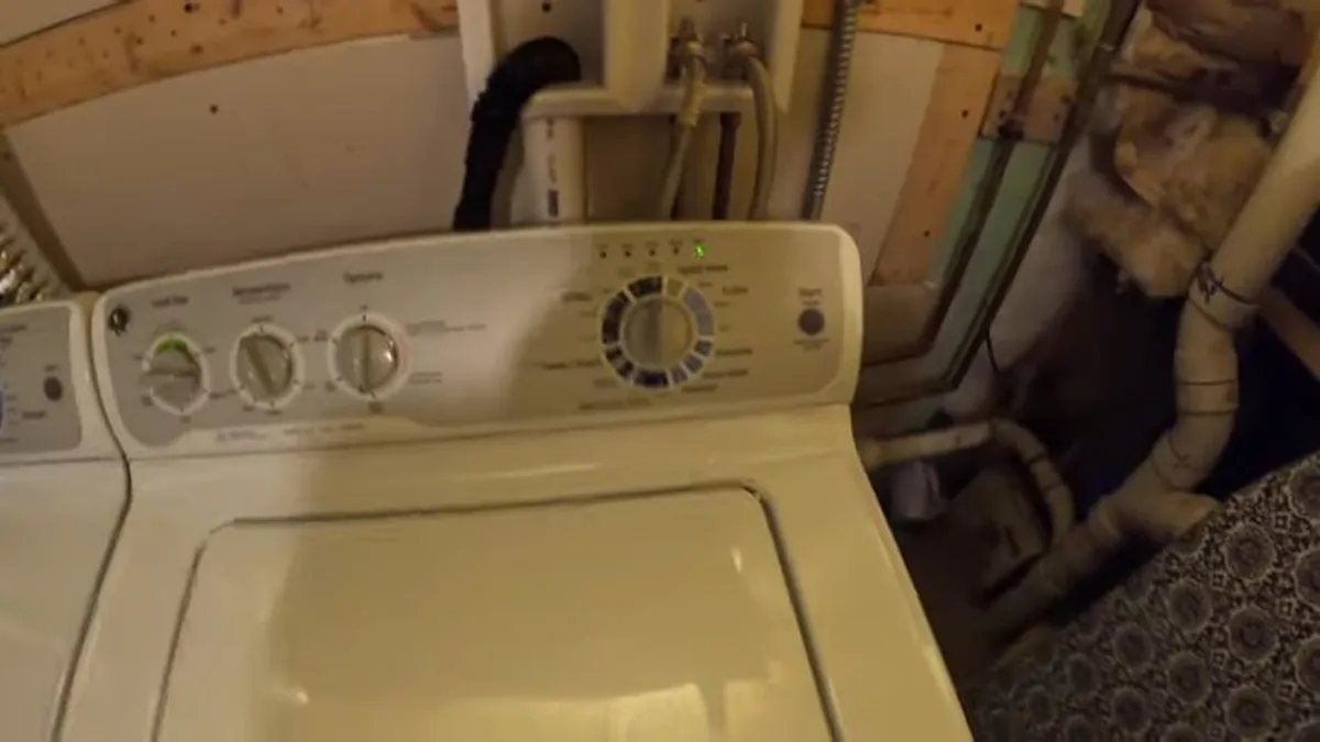washer and dryer sit beside visible utility lines in a basement laundry area during a plumbing service call in Maricopa, AZ