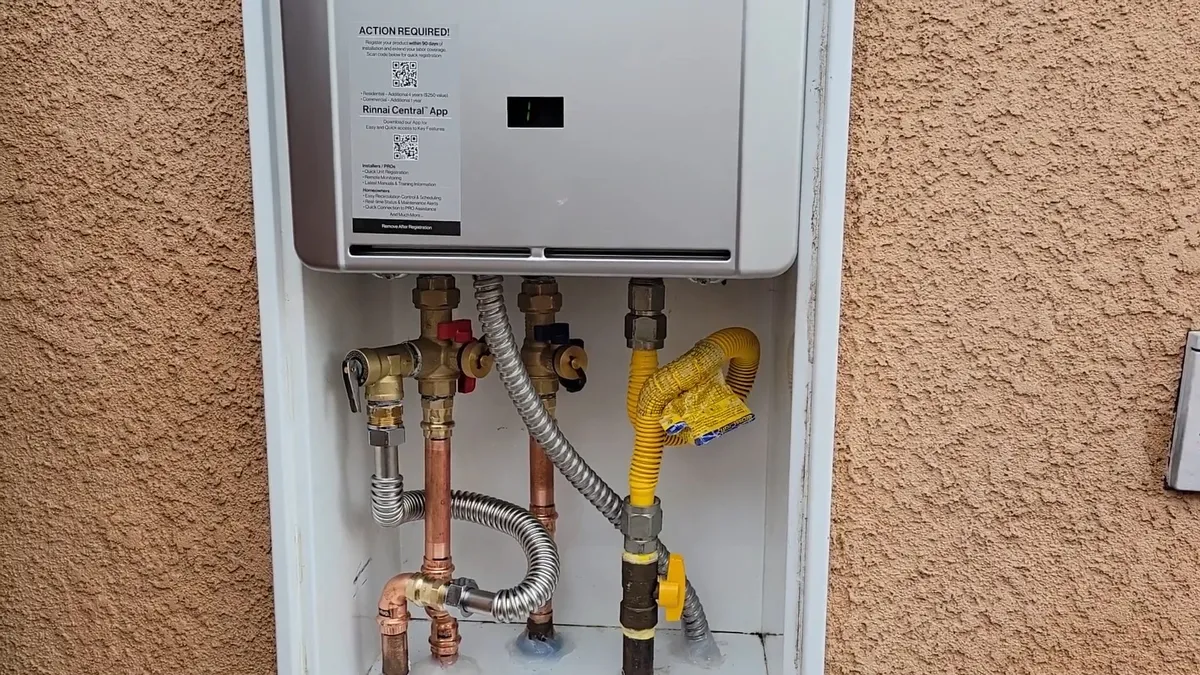compact outdoor tankless water heater is fully connected on a stucco wall for tankless water heater services in maricopa, az in Maricopa