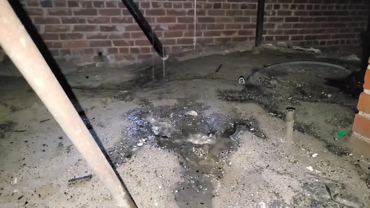 Wet soil and staining mark a leak area in a low crawlspace during a plumbing service call in Maricopa, AZ