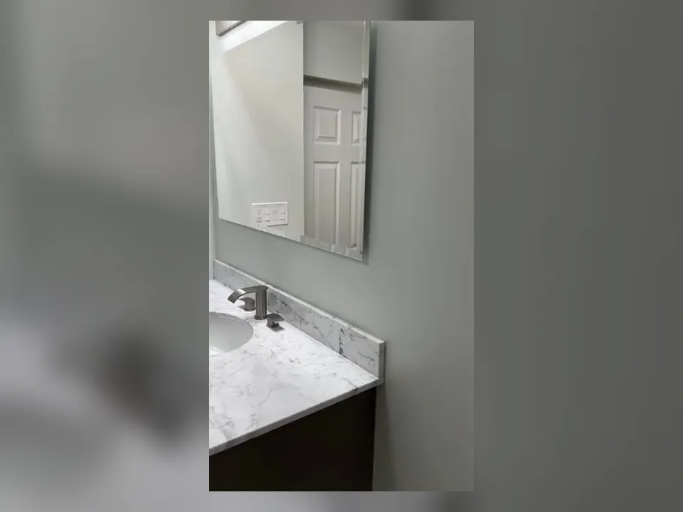 narrow bathroom vanity and mirror are installed beside finished gray walls illustrating Walk-In Shower Conversions in Province, Maricopa: What the Plumbing Scope Actually Involves