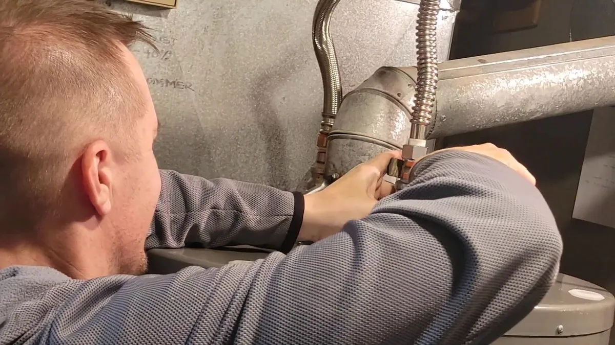 technician secures the metal vent connection above a gas water heater for water heater installation & replacement in maricopa, az in Maricopa