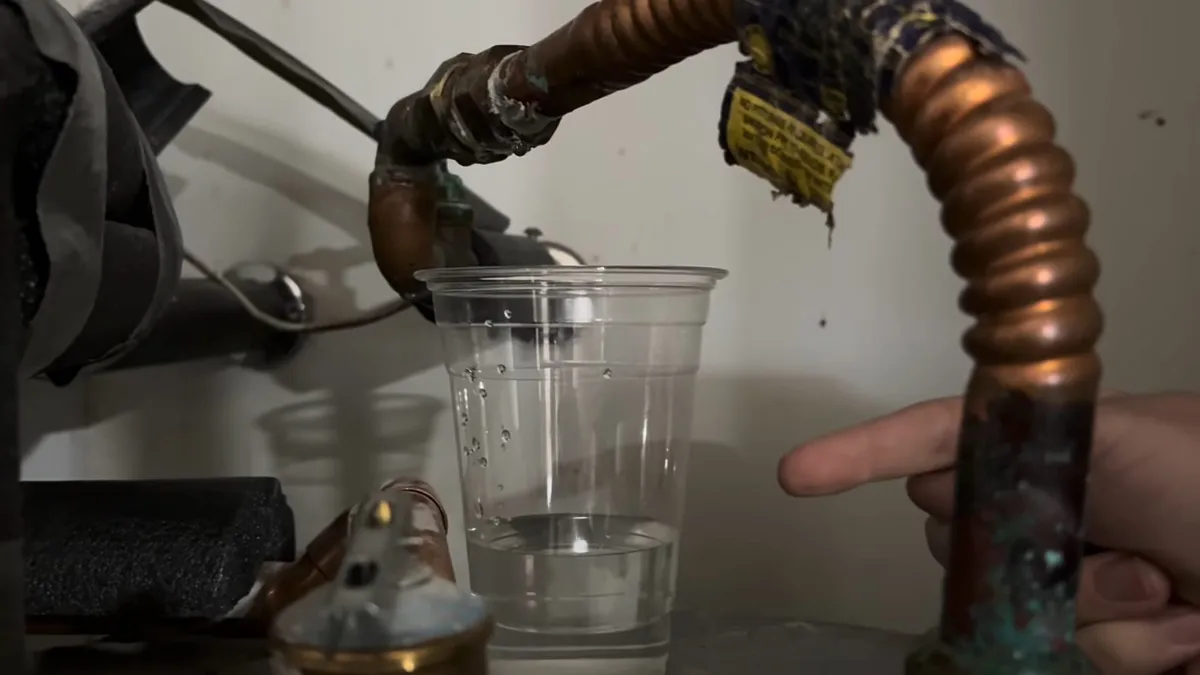 corroded flexible water-heater inlet line drips into a clear cup for water heater repair in maricopa, az in Maricopa