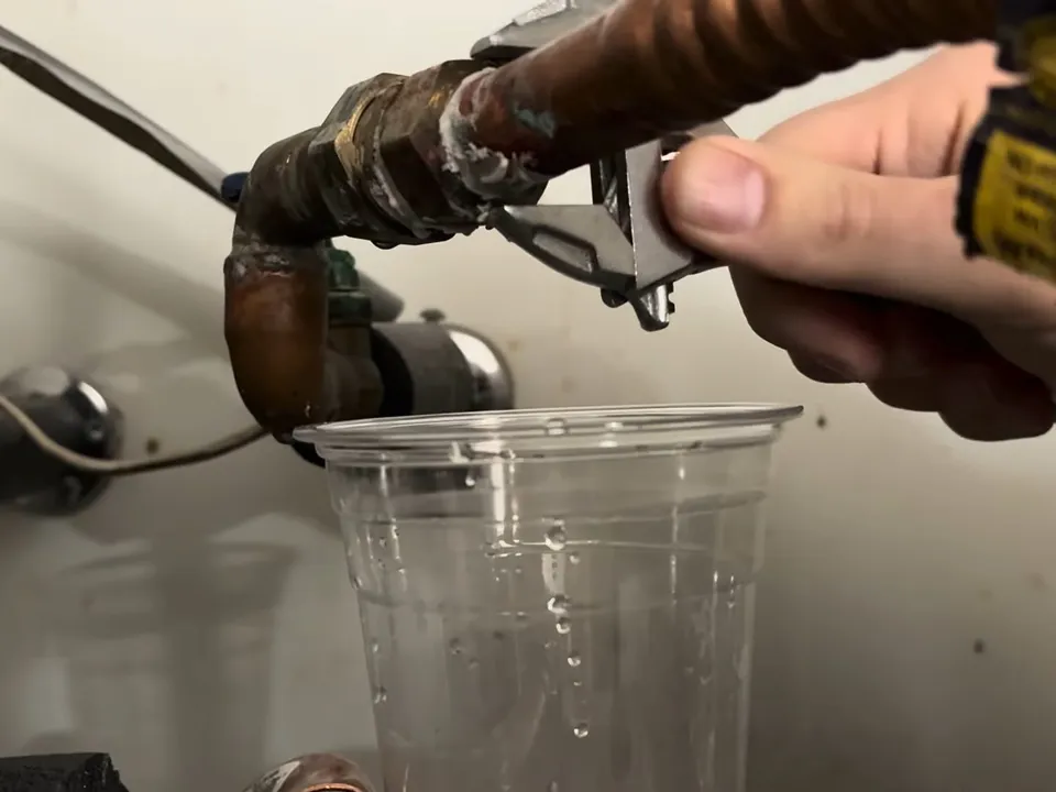 slow leak from a corroded heater connector is collected in a clear cup for water heater repair in maricopa, az in Maricopa