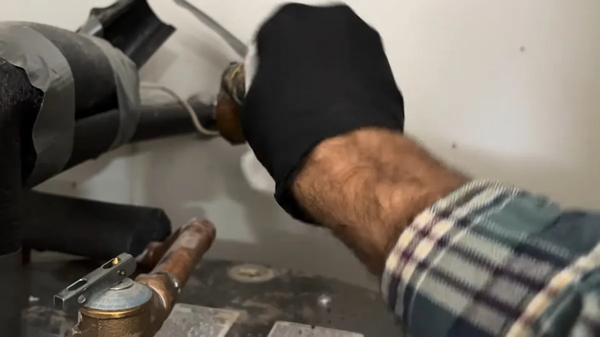 technician removes an old flexible inlet line from a water heater connection for water heater repair in maricopa, az in Maricopa