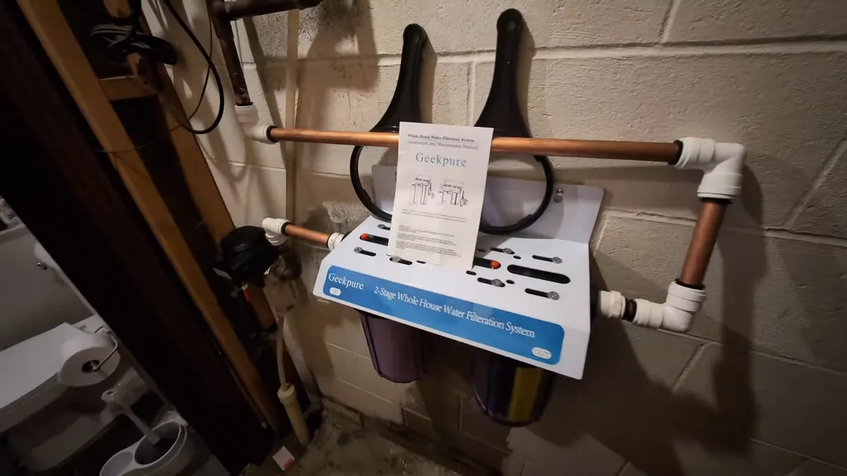 wall-mounted filter manifold is connected to copper and PVC lines in a utility area illustrating Softener Plus RO: Why Maricopa Homeowners Need Both Systems and How They Work Together