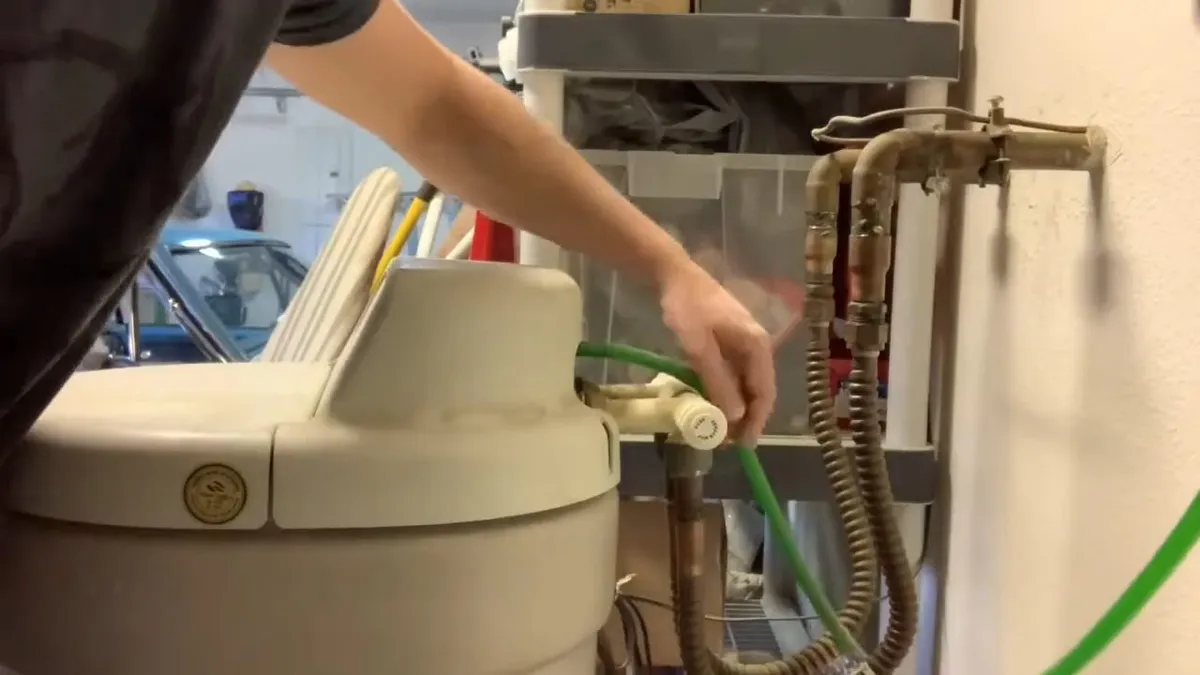 technician disconnects a green service hose from the top of a water softener for water softener installation & repair in maricopa, az in Maricopa